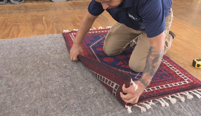 Expert installing custom rug pad on floor