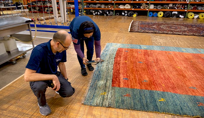 Two Dalworth Rug Cleaning technicians performing an initial inspection on area rug