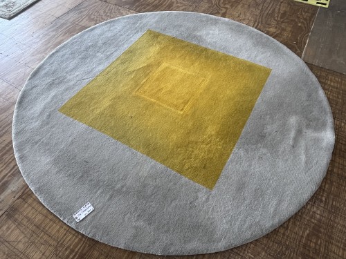 A large modern round area rug featuring a plush grey field and a central yellow geometric square design, completely deep-cleaned, sanitised for pet odours, and pile-restored on a workshop floor.