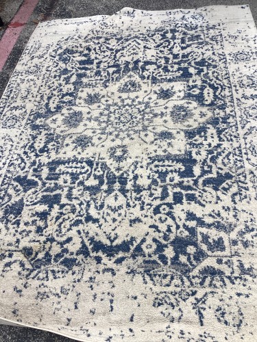 Professional residential rug cleaning service repairing a frayed serge and removing heavy soil and furniture marks.