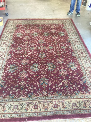 Professional residential rug cleaning service restoring a red patterned rug with moderate soil and furniture marks.