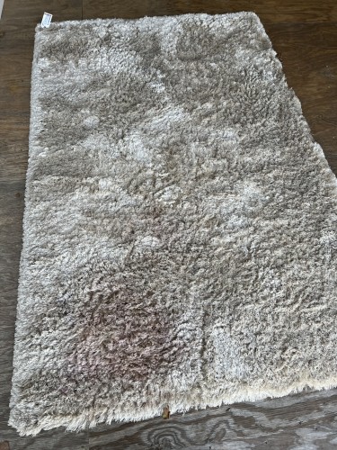 Residential shaggy rug showing faded areas and moderate soil before professional cleaning.