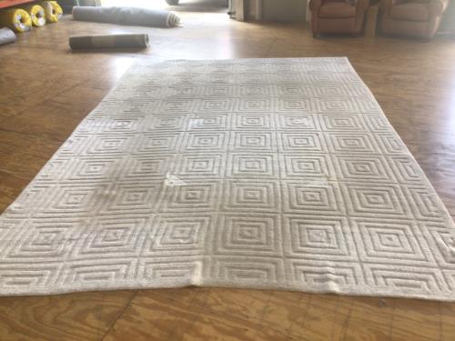 Professional residential rug cleaning and serge repair service for a white geometric patterned area rug.