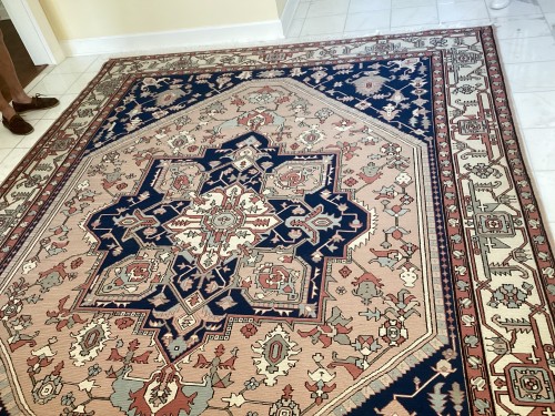 A large, intricately patterned residential area rug after professional cleaning and repair by Dalworth Rug Cleaning, showcasing its restored nap, vibrant colors, and smooth texture without pulled fibers or white knots, lying on a light tiled floor.