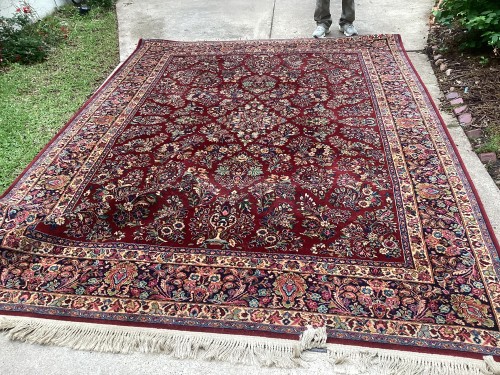 A large traditional Persian area rug with an intricate red and navy floral medallion design, completely deep-cleaned, with fully restored pile and neatly aligned white decorative fringes.