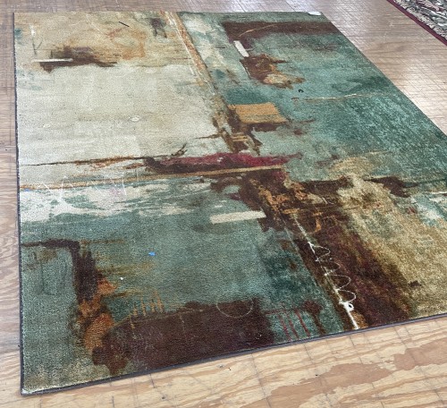 A plush residential area rug featuring an abstract teal, brown, and cream pattern completely cleaned, groomed, and prepped for delivery back to the client.