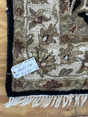 Close-up of a residential rug's border, highlighting the frayed serging and a faded section, along with a service tag, indicating areas addressed by Dalworth Rug Cleaning's repair and cleaning services.