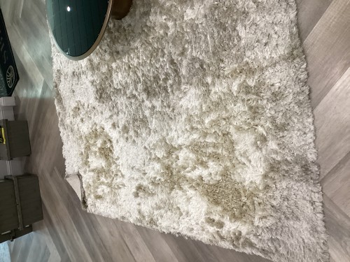 A plush white high-pile shag rug completely deep-cleaned, sanitised, and pile-restored to eliminate furniture marks and pet staining on a modern wood floor.