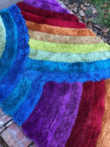 A freshly cleaned vibrant multi-colored shaggy rug with distinct rainbow stripes, showcasing the successful removal of pet stains by Dalworth Rug Cleaning.