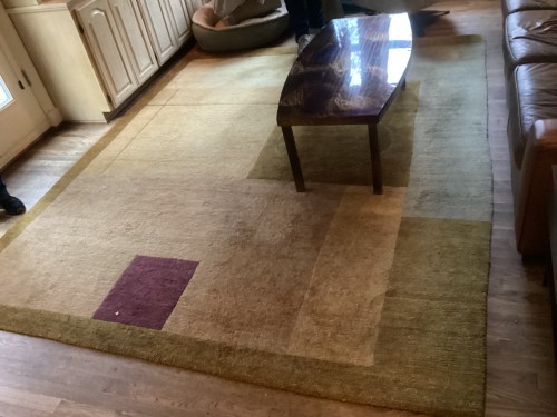 Professional cleaning of a large residential area rug with a modern geometric design in a living room by Dalworth Rug Cleaning.