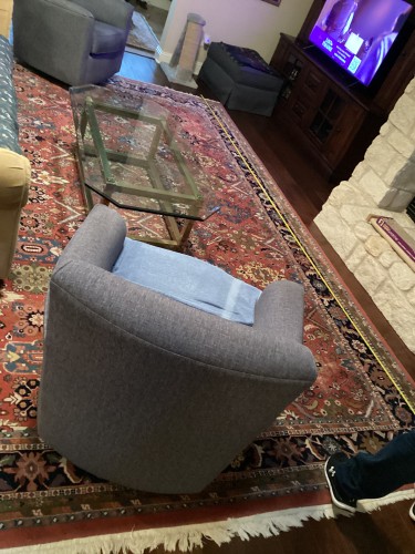 An expansive, traditional oriental area rug in deep red, blue, and cream tones covering a living room floor, with a modern gray armchair and a glass coffee table situated on it, highlighting residential rug cleaning services by Dalworth Rug Cleaning.