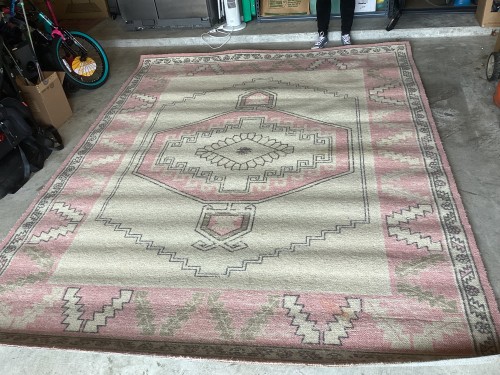 A large traditional geometric southwestern-style area rug in cream, pink, and grey pastel tones, completely deep-cleaned, sanitised for pet odours, and pile-restored on a garage concrete floor.