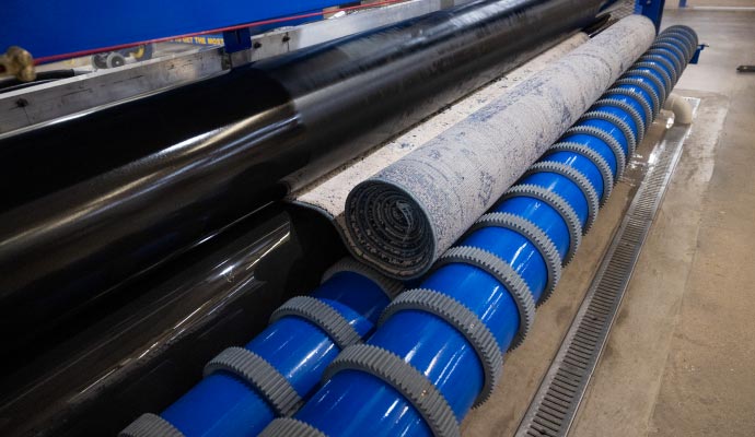 Rolled rug placed on a blue rubber conveyor belt