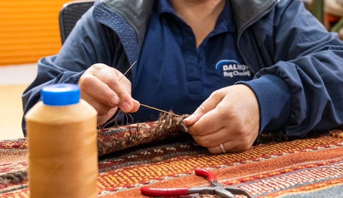 Skilled technician restoring backing of a rug.