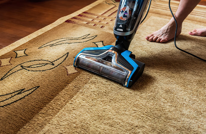 Household rug cleaning with a vacuum cleaner in use.
